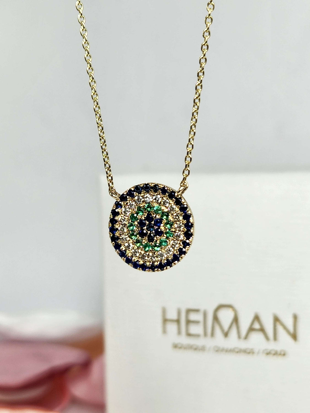 Round eye necklace 14k gold, sapphires, emeralds, and diamonds.
