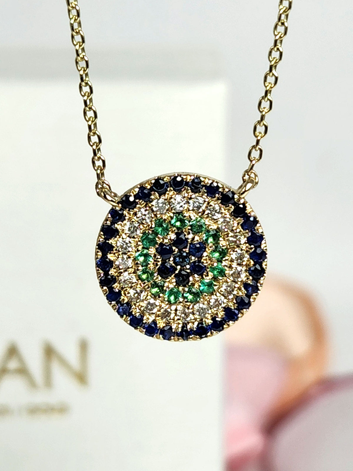 Round eye necklace 14k gold, sapphires, emeralds, and diamonds.