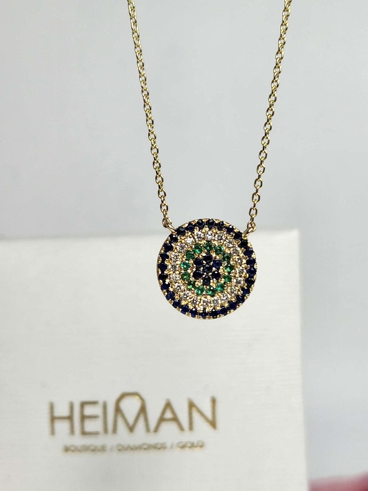 Round eye necklace 14k gold, sapphires, emeralds, and diamonds.